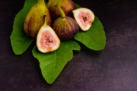Figs fruit are on fresh green leaves on vintage background. High Vitamins fruit. Close-up photo....