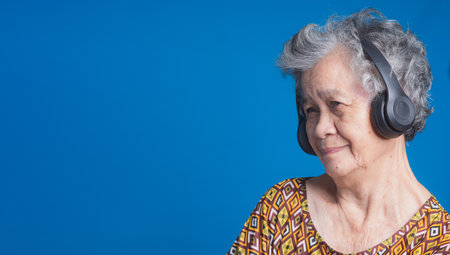 Senior woman happiness concept. An elderly Asian woman with short gray hair wearing wireless...