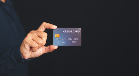 Hand of holding a mockup blue credit card while standing with a black background in the studio....