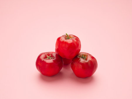 Close-up of three ripe red cherries isolated on a pink background. High vitamin C and antioxidant fruits. Concept of healthy fruits.の写真素材