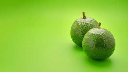 Two fresh avocados are isolated on a green background. High Vitamin fruit. Space for text. Healthy fruit concept.の写真素材