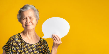 Concept of question mark speech bubble. An elderly Asian woman with short gray hair holding a blank...