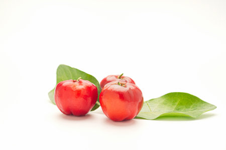 Ripe red acerola cherry fruit and green leaves isolated on white background. High vitamin C and antioxidant fruits. Top view. Space for text. Concept of healthy fruits.の写真素材