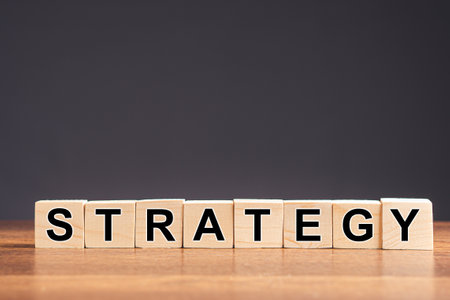 Strategy word written on cube shape wooden blocks on wooden table with a gray background. Space for...
