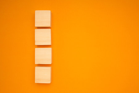 Top view of blank four wooden cubes on a yellow background with space for text.の写真素材
