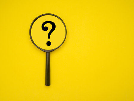 Top view of a magnifying glass with question mark isolated on a yellow background. Space for textの写真素材