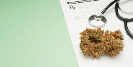 Top view of a stethoscope and dry marijuana buds flowers on the medical prescription sheet isolated on a green background. Space for text. Herbal, medical and healthcare conceptの写真素材