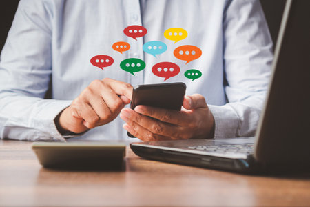 Social network and live chat chatting concept. Close-up of hands using mobile phone with colorful chat icons on application communication digital web and social media.の写真素材