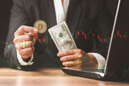 Businessman holding a bitcoin and US dollar banknotes while sitting in the office. Bitcoin is a...
