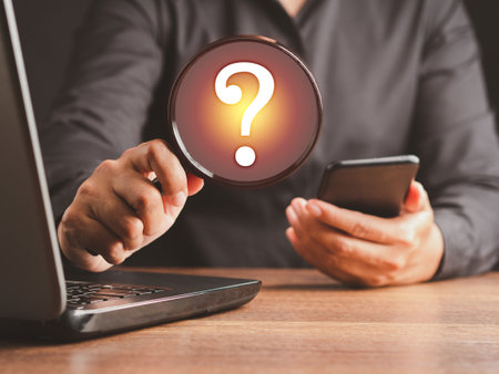 Question mark concept. A businessman is holding a magnifying glass looking at a question mark...
