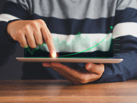 Businessman holding of tablet and showing a graph of business statistics diagram on virtual screen while sitting in the office. A business strategy, technology, and investment concept.の写真素材