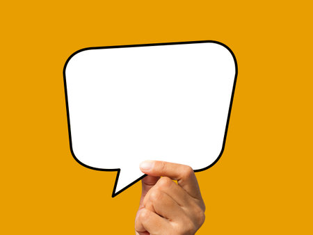 Hand holding of an empty white speech bubble against an orange background. A speech bubble concept....