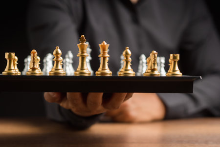 Business strategy ideas and investment. Businessman in a black shirt holding a chessboard. Close-up photoの写真素材