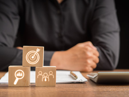 Concept of business achieving goal, objective target, and teamwork. Close-up of wooden cubes with icon business strategy and businessman sitting in the office. Space for textの写真素材