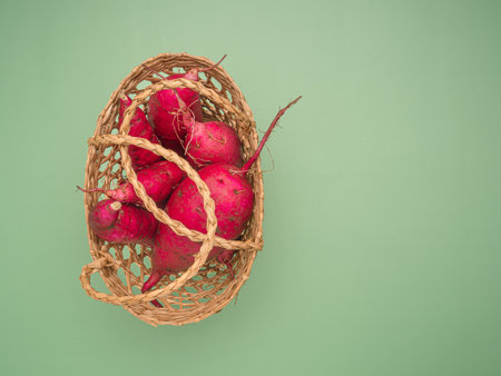 Top view of Japanese sweet potatoes in a basket over a green background. Space for text. Close-up photo. Healthy food conceptの写真素材