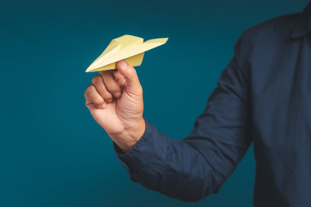 Business startup concept. Hand holding a yellow rocket paper on a blue background. Space for textの写真素材