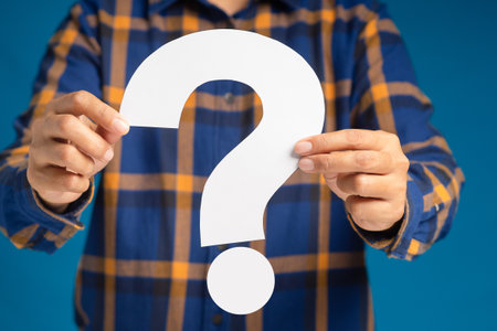 Question mark symbol concept. Hands holding a white question mark paper while standing on a blue...