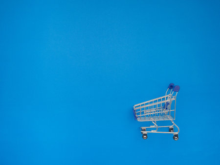 An empty mini shopping trolley over blue background. Supermarket grocery pushcart. Business and e-commerce conceptの写真素材