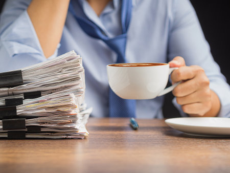 Businessman hand holding a cup of coffee sitting working at the office. Close-up photo. Beverage and relaxation conceptの写真素材