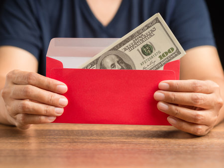 Man in casual holding a red envelope with money. Close-up photoの写真素材