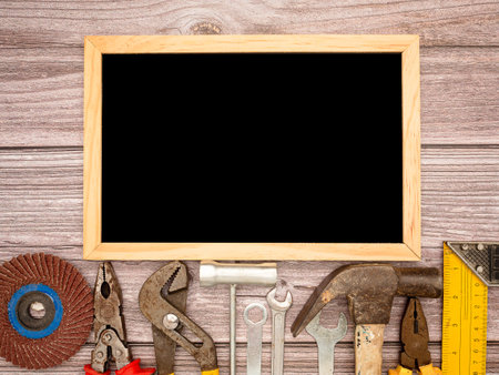 A blank mini chalkboard and construction tools, a hammer, screwdriver, screws, and pliers on a wooden table. Top view. Space for textの写真素材