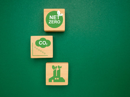 Net-zero greenhouse gas emissions target. Climate-neutral long-term strategy. Wooden cubes with green icons over a green background. Close-up photo. Space for textの写真素材