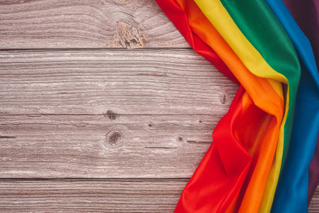Top view of the rainbow flag or LGBT over a wooden table with copy space for text. Flat layの写真素材