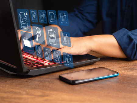 Person working at a laptop with digital documents displayed on a virtual screen. Business and...