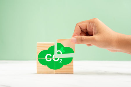 Wooden cubes with CO2 green icons over a marble floor against a green background. Renewable energy. Net-zero greenhouse gas emissions target. Green industries business and CO2 emission conceptの写真素材