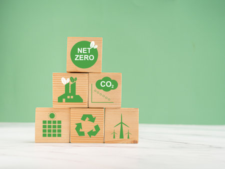 Net-zero emissions in 2050. World Earth day concept. Save earth and environment, and carbon neutral. Wooden cubes with eco-friendly icons over a marble floor against a green backgroundの写真素材