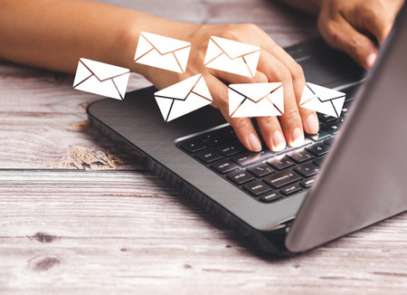 Businessman receives a new message with email icons on a virtual screen while sitting in the office. Email notification on the laptop. Email marketing concept. Close-up photoの写真素材