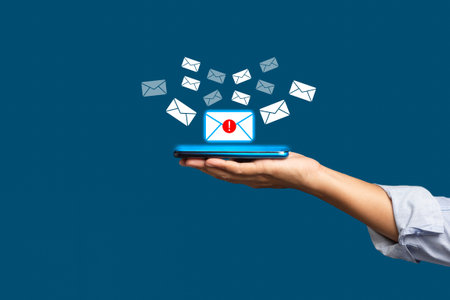 Email marketing concept. A smartphone on the palm with receives a new message with email icons on a...