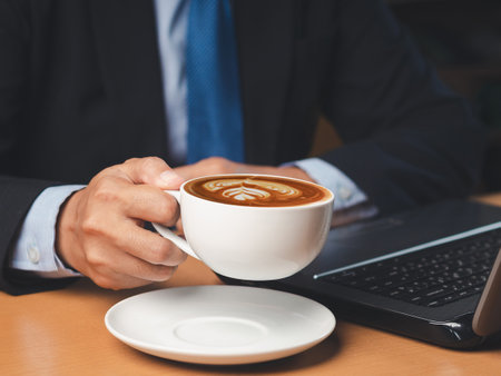Businessman hand holding a cup of coffee sitting working at the office. Close-up photo. Beverage and relaxation conceptの写真素材