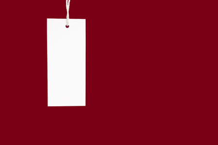 A blank white label or price tag against a red background. Space for text. Close-up photo. Shopping and price tag conceptの写真素材