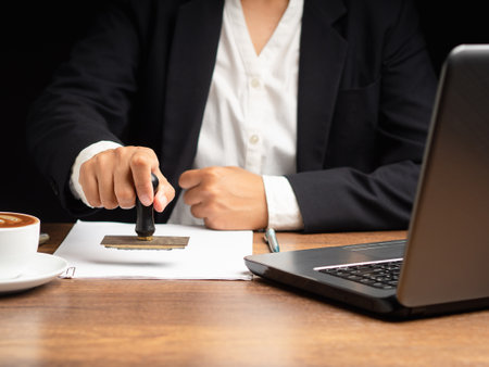 Businesswoman stamping approved on documents while sitting working in the office. Close-up photoの写真素材
