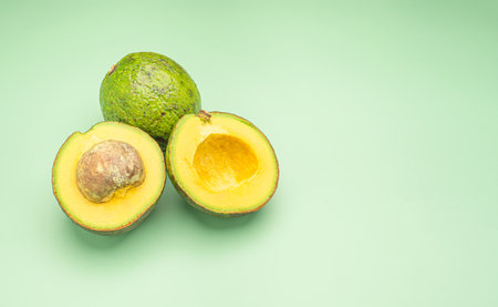 Avocados on a green background. Top view. Space for text. Healthy fruits concept
