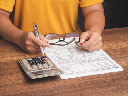Tax day concept. Businessman using a tax form to complete individual income tax payment form. Close-up photoの写真素材