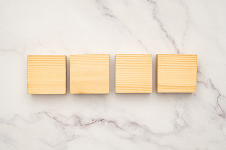 Top view of blank four wooden cubes on a marble background. Space for text