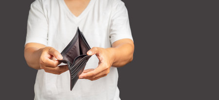 Bankruptcy concept. A man hands open an empty wallet standing on a gray background. No money to pay...
