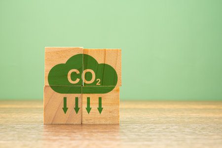 Wooden cubes with a green CO2 icon with down arrows on a wooden table. Net-zero emissions in 2050....