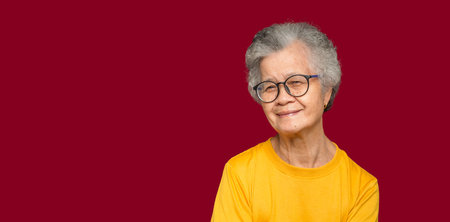 Portrait of an elderly Asian woman with short gray hair looking at the camera with a smile while...