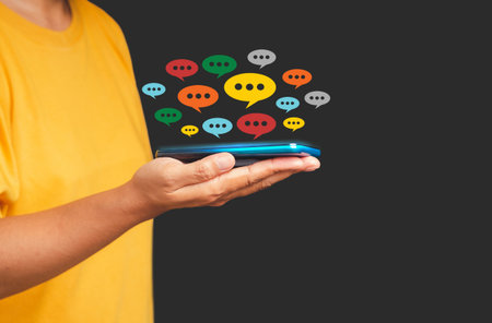 Social network and live chat chatting concept. Close-up of hand using mobile phone with colorful chat icons on application communication digital web and social mediaの写真素材
