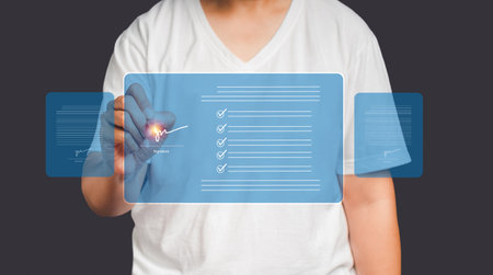 Signature concept. Close-up of hand using a pen to sign documents on a virtual screen while standing on a gray background. Business, technology, paperless office, and document managementの写真素材