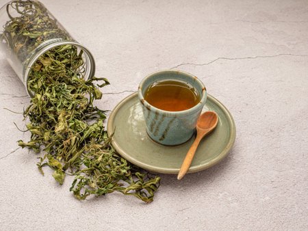 Dry cannabis leaf tea outside a box and marijuana tea cup on a table. Textured marijuana leaves. Concept of beverage with cannabis herbの写真素材