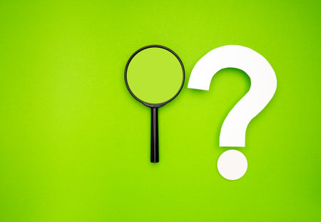 Search and question mark concept. A magnifying glass and a white question mark symbol are on a light...