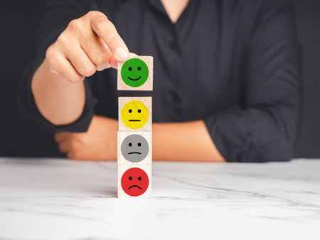 Positive feedback concept. The customer chooses a green happy mood icon on a wooden cube over a marble table. Happy and sad mood icons. Feedback emotion scale.The survey satisfaction researchの写真素材