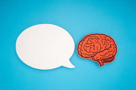 White speech bubble and a brain shape made from paper on a blue background. Awareness of Alzheimer's, Parkinson's disease, dementia, stroke, seizure, or mental health. Neurology and Psychology careの写真素材