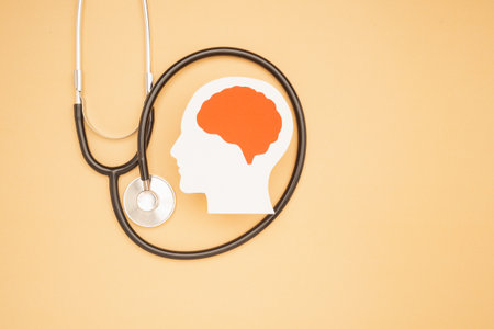 A brain shape made from paper and a stethoscope on a light orange background. Awareness of Alzheimer's, Parkinson's, dementia, stroke, seizure, or mental health. Neurology and Psychology careの写真素材