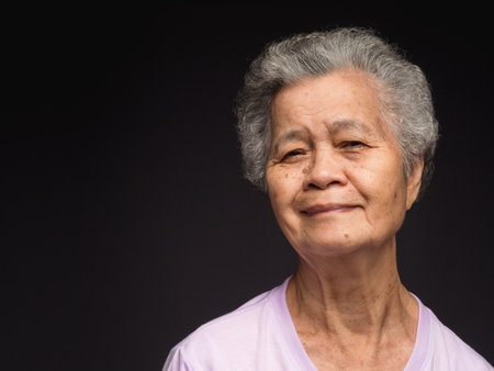 Portrait of an elderly Asian woman with short gray hair looking at the camera with a smile while...