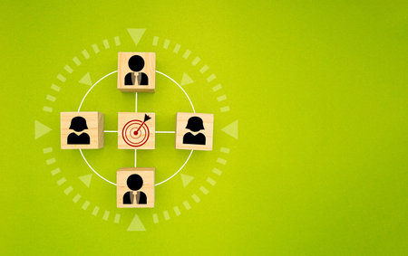 Wooden cubes with people icons focus on the goal over a green background. Teamwork and unity concept. Space for text. Flat layの写真素材